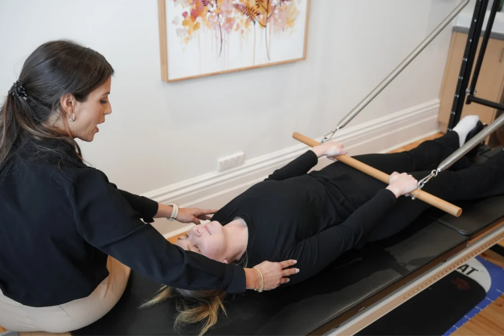 Physiotherapist providing hands-on guidance during a Clinical Pilates reformer session at Modern Medicine in Ballarat